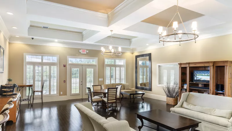 Bright and welcoming clubhouse at Lauren Ridge Apartments with cozy couches, wood accents, and a flat-screen TV, ideal for social gatherings.