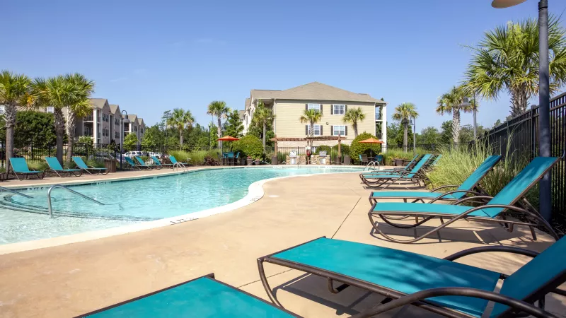Expansive poolside view with lounge chairs, shaded umbrellas, and nearby grilling stations at Lauren Ridge’s outdoor amenity area.