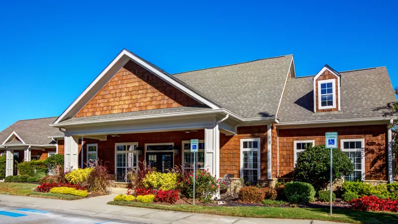 Main leasing office at Lauren Ridge Apartment Homes, featuring warm cedar shake exterior, manicured landscaping, and accessible parking.