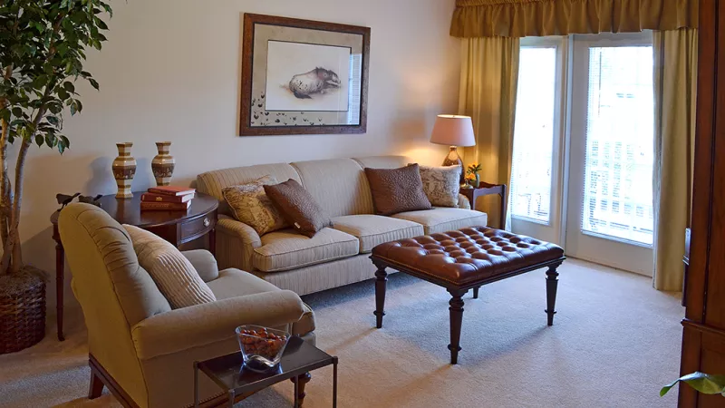 Bright living room with plush seating, elegant decor, and large windows with patio access at Market Street Station apartments.