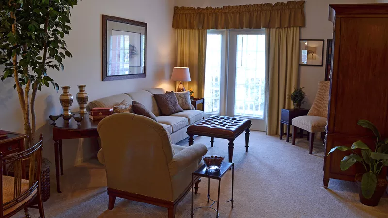 Spacious living room with cozy furniture, carpeted flooring, and double French doors at Market Street Station apartments.