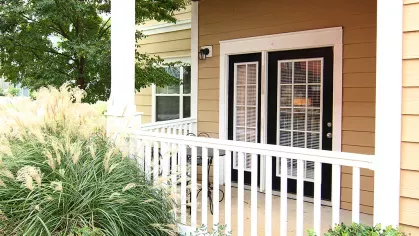 Private patio entryway – Covered private patio with double French doors and surrounding landscaping, perfect for enjoying the outdoors.