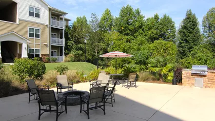 Spacious patio at Reed Creek Apartments featuring a fire pit, outdoor seating, and a built-in grill station.