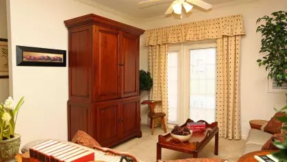 Living room with wooden armoire, ceiling fan, and access to private balcony at Reserve at Mill Creek