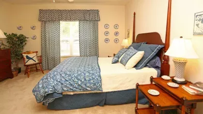Spacious bedroom with a wooden four-poster bed, blue patterned bedding, and matching curtains at Reserve at Mill Creek.