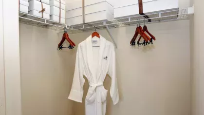 Walk-in closet with wooden hangers, storage boxes, and a hanging white robe at Reserve at Mill Creek.
