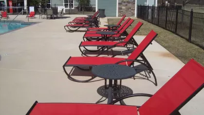 Row of red mesh pool loungers beside the community pool and clubhouse patio