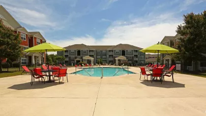 Wide view of the pool area featuring red patio furniture and lime green umbrellas at Reserve at Mill Creek