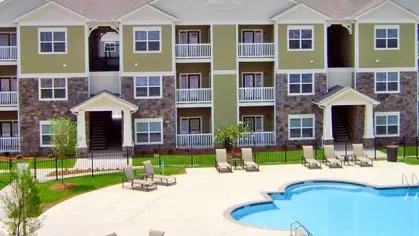 Bird’s-eye view of community pool with surrounding tan lounge chairs and apartment balconies