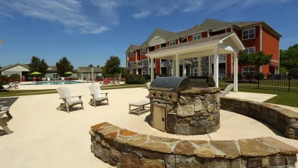 Outdoor grilling area with stainless steel BBQ and stone seating wall overlooking pool and patio seating