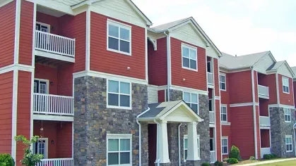  Red apartment building with white balconies and stone accents at Reserve at Mill Creek.