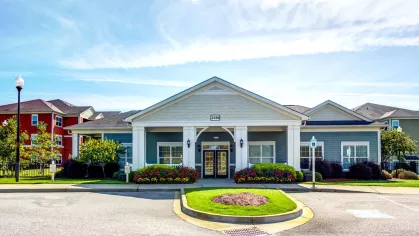 Leasing office at Reserve at Mill Creek with blue siding, white trim, and colorful flowerbeds.