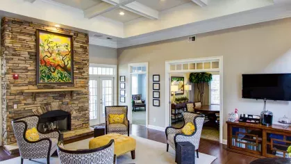 Clubhouse lounge at The Heights at Lake Murray with stacked stone fireplace, patterned chairs, and vibrant artwork