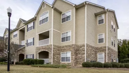 Charming exterior of The Heights at Lake Murray apartments with stone base, beige siding, and arched patios