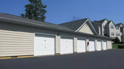 Row of private garages with white doors and beige siding at The Heights at Lake Murray apartment community in Irmo SC