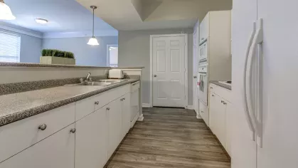 Long countertop space and dual sinks in a bright kitchen at The Saulet Apartments, perfect for cooking and entertaining.