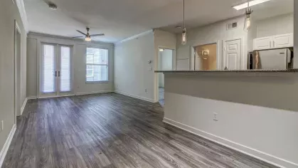 Unfurnished open living space with wood-style floors, ceiling fan, and natural light at The Saulet Apartments