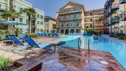 Resort-style swimming pool with lounge chairs and tropical landscaping at The Saulet Apartments