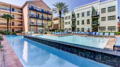 Luxury lap pool with elevated lounging deck and vibrant surroundings at The Saulet Apartments in New Orleans.