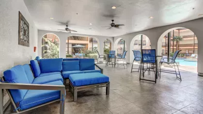 Covered outdoor lounge at The Saulet luxury apartments in New Orleans with modern blue cushioned seating and poolside views.