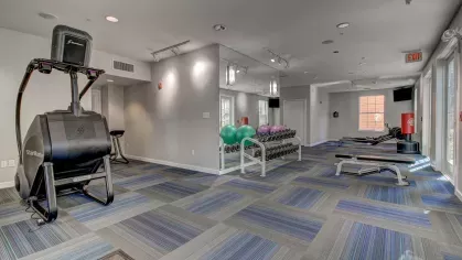 Spacious fitness center at The Saulet featuring StairMaster, free weights, and exercise balls for resident workouts.