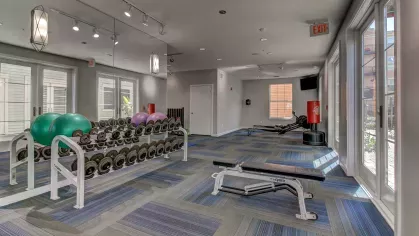 The Saulet apartment gym with dumbbell rack, flat bench, and strength training equipment in New Orleans, LA.