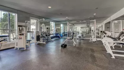 Fully loaded weight room with mirrored walls and resistance training machines at The Saulet apartments