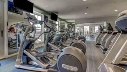 Elliptical machines and wall-mounted TVs in the upscale fitness center at The Saulet apartments in New Orleans.