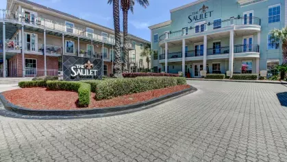 Grand entrance of The Saulet apartments in New Orleans with landscaped driveway and community signage
