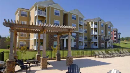 Modern four-story apartment buildings at Knob Creek Apartments with balconies, stone accents, and a pergola-covered seating area.