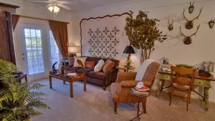 Stylish model apartment living room at Knob Creek Apartments with warm decor, a large windowed door, and unique wall art.