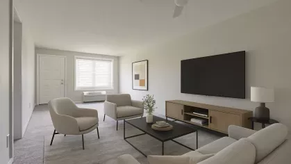 Spacious living room at Astorwood Apartments with virtual staging, including a cream-colored sofa set, large wall-mounted TV, and modern décor