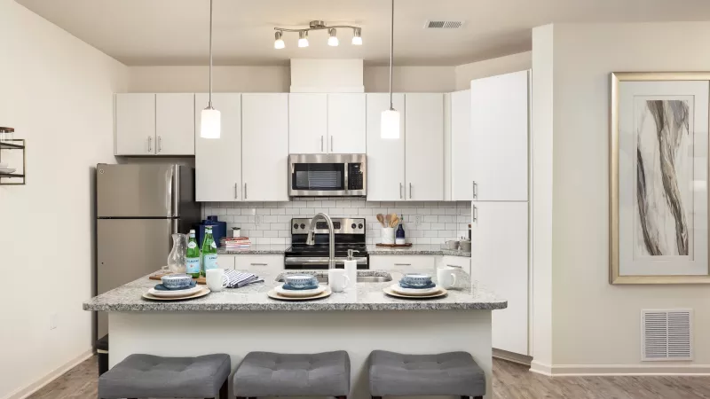 Spacious kitchen with island seating, pendant lighting, and subway tile backsplash at Avery Turkey Creek Apartments.