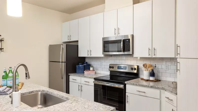 Stainless steel refrigerator, microwave, and oven in a contemporary apartment kitchen at Avery Turkey Creek.