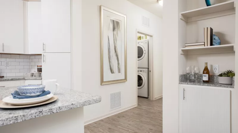 Open kitchen with granite countertops, white cabinets, and in-home washer and dryer nearby at Avery Turkey Creek Apartments.