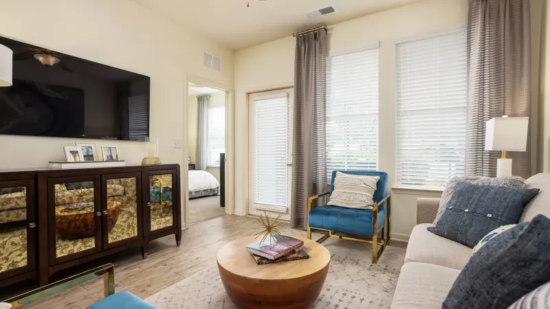 Bright apartment living room with natural light, neutral décor, and access to private bedroom at Avery Turkey Creek.