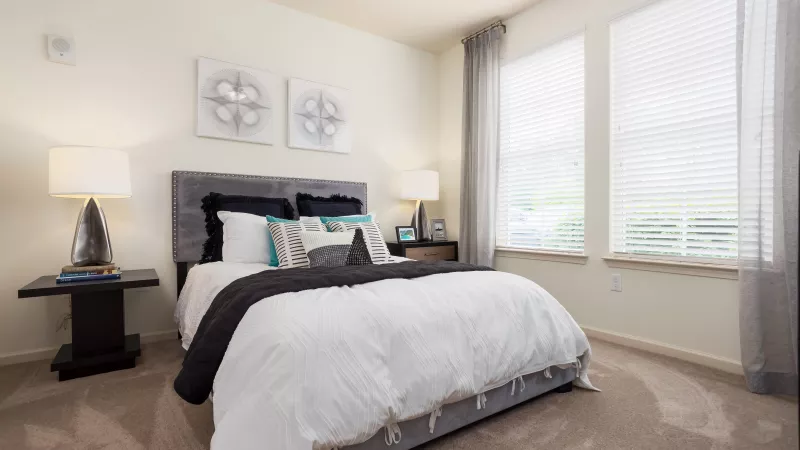 Spacious bedroom with contemporary furniture, neutral walls, and natural light at Avery Turkey Creek Apartments.