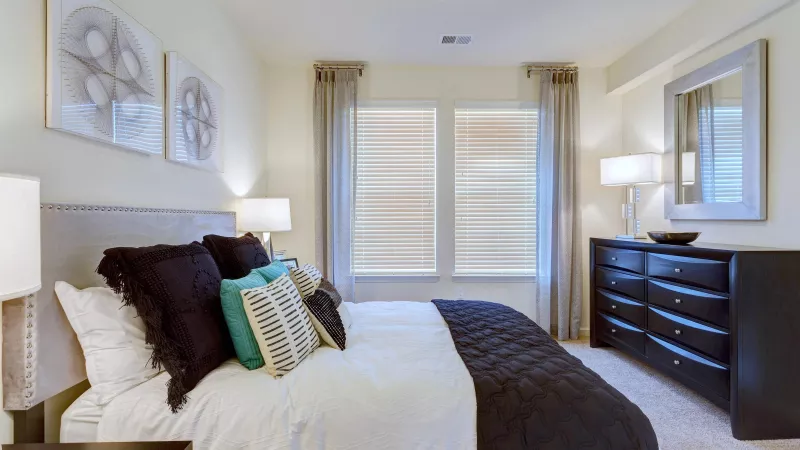 Cozy bedroom with decorative wall art, modern nightstands, and ample windows at Avery Turkey Creek Apartments.