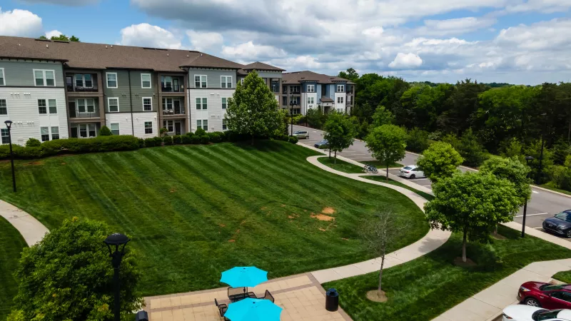 Outdoor lawn and cornhole game area surrounded by Avery at Turkey Creek apartment buildings