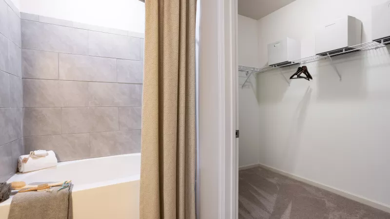 Modern bathroom at Avery Turkey Creek Apartments with tiled shower, soaking tub, and walk-in closet.