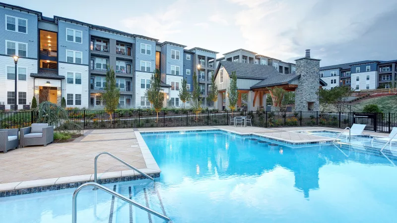 Sparkling pool with landscaped courtyard and modern apartment buildings in the background at Avery Turkey Creek.