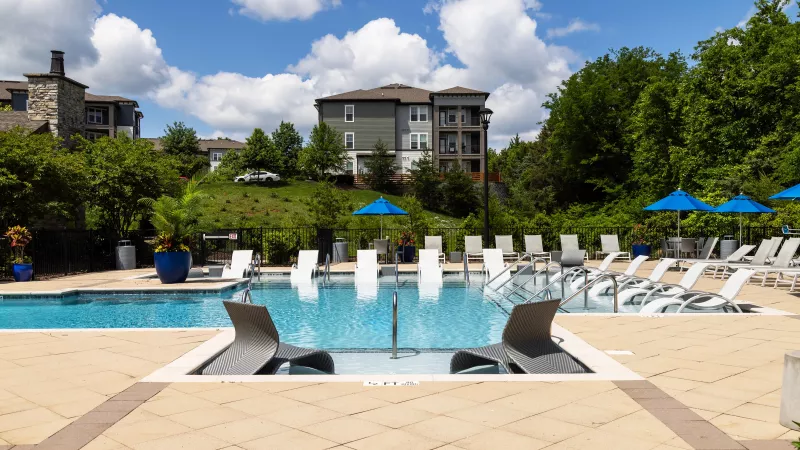 Sparkling swimming pool at Avery Turkey Creek with lounge chairs, sundeck seating, and landscaped greenery.