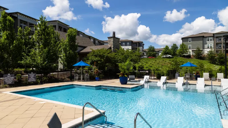 Scenic pool view at Avery Turkey Creek with modern sundeck seating, umbrellas, and landscaped surroundings.