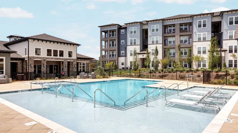 Modern apartment community pool at Avery Turkey Creek with in-water chaise loungers and spacious sundeck seating.