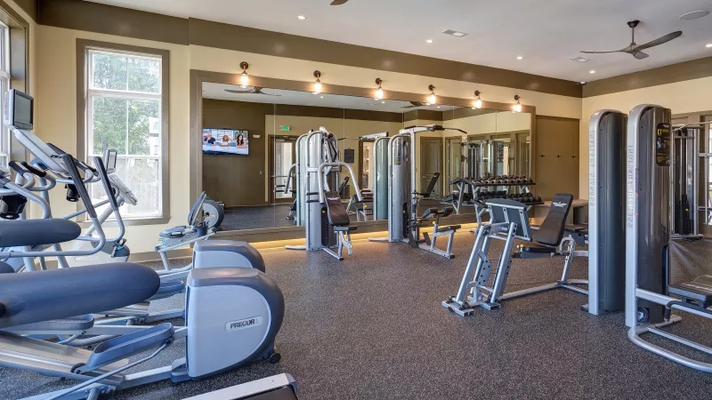 Strength training and cardio fitness center at Tapestry Turkey Creek with spacious mirrored walls.