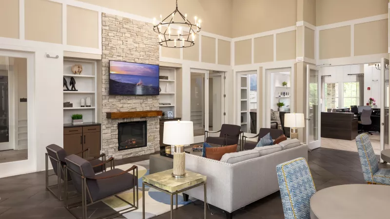 Resident clubhouse lounge at Avery Turkey Creek with stone fireplace, mounted TV, and modern seating.