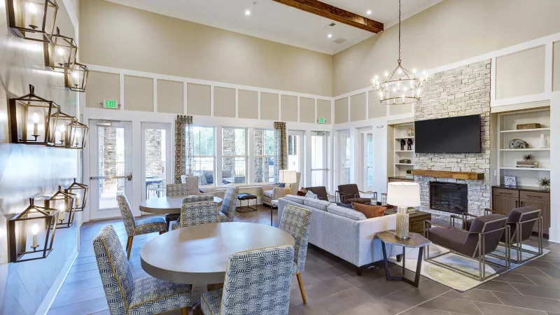 Clubhouse common area with stone fireplace, chandelier, and lounge seating at Avery Turkey Creek Apartments.