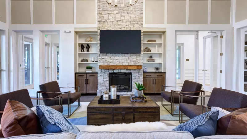 Clubhouse interior at Avery Turkey Creek with stone fireplace, modern furniture, and mounted flat-screen TV.