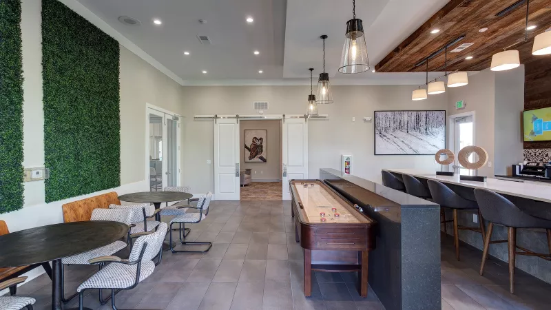 Resident game room at Avery Turkey Creek with shuffleboard table, café seating, and modern décor.