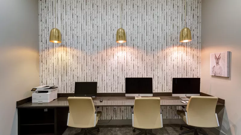 Workstations with iMac computers and pendant lights in the resident business center at Avery Turkey Creek.